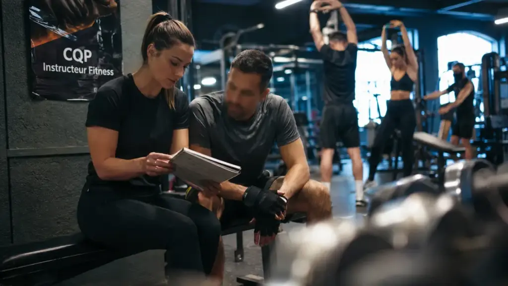 CQP coach sportif : entraîneuse montre un carnet de séance en salle de sport