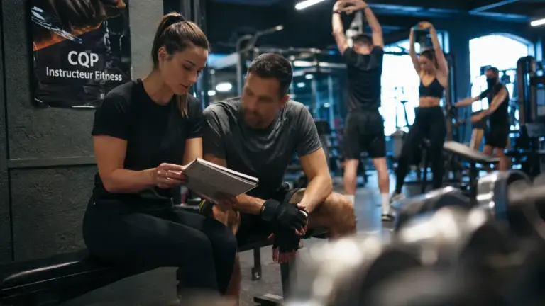 CQP coach sportif : entraîneuse montre un carnet de séance en salle de sport